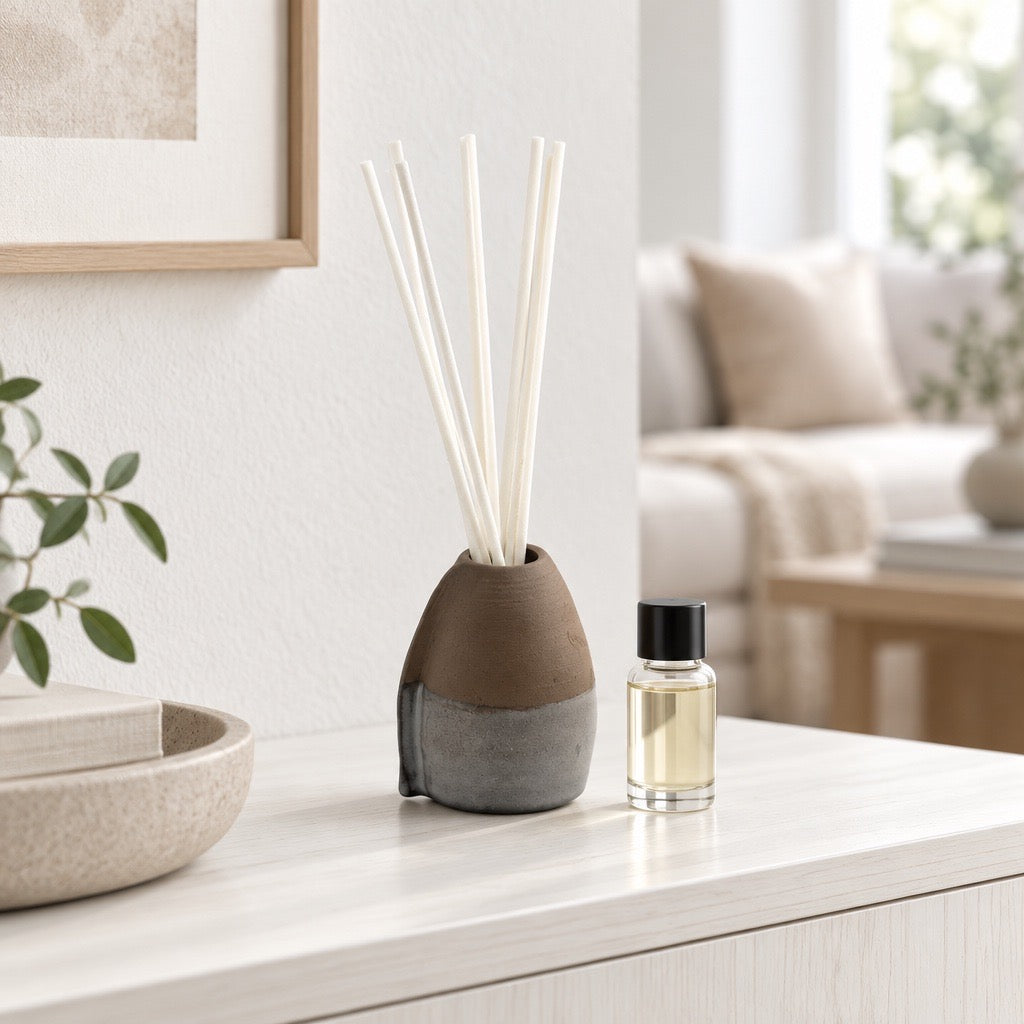 Diffuseur d'huile essentielle VULCAIN en faïence noire, tourné et fait main par Terresme posé sur une table dans une entrée avec une bouteille d'huile essentielle à côté 