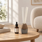 Diffuseur d'huile essentielle VULCAIN en faïence noire, tourné et fait main par Terresme posé sur une table basse de salon avec une bouteille d'huile essentielle à côté 