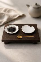 Set de quatre coupelles feuille de capucine en grès blanc, fait main par Terresme mise en scène sur tablette avec feuilles de thé, cuillère dorée  et théière.