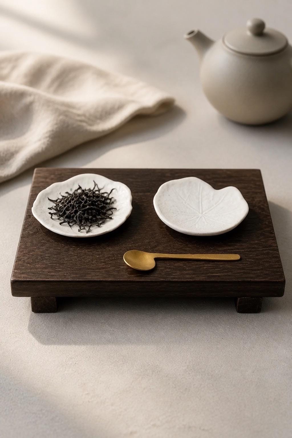 Set de quatre coupelles feuille de capucine en grès blanc, fait main par Terresme mise en scène sur tablette avec feuilles de thé, cuillère dorée  et théière.