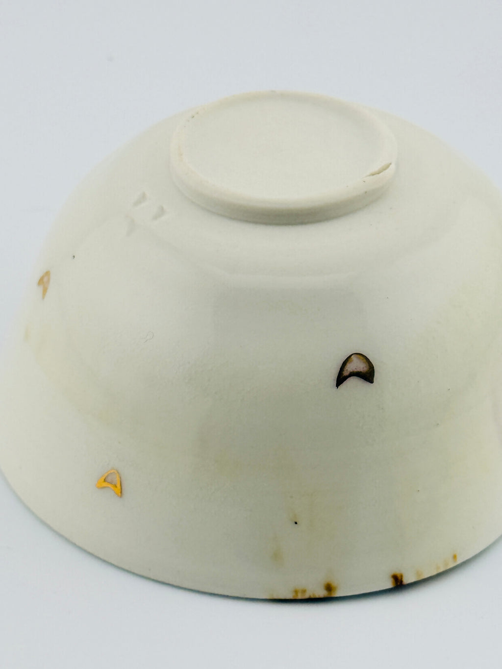 Dessous d’une tasse verseuse katakuchi blanche, avec un petit cœur à l’or
