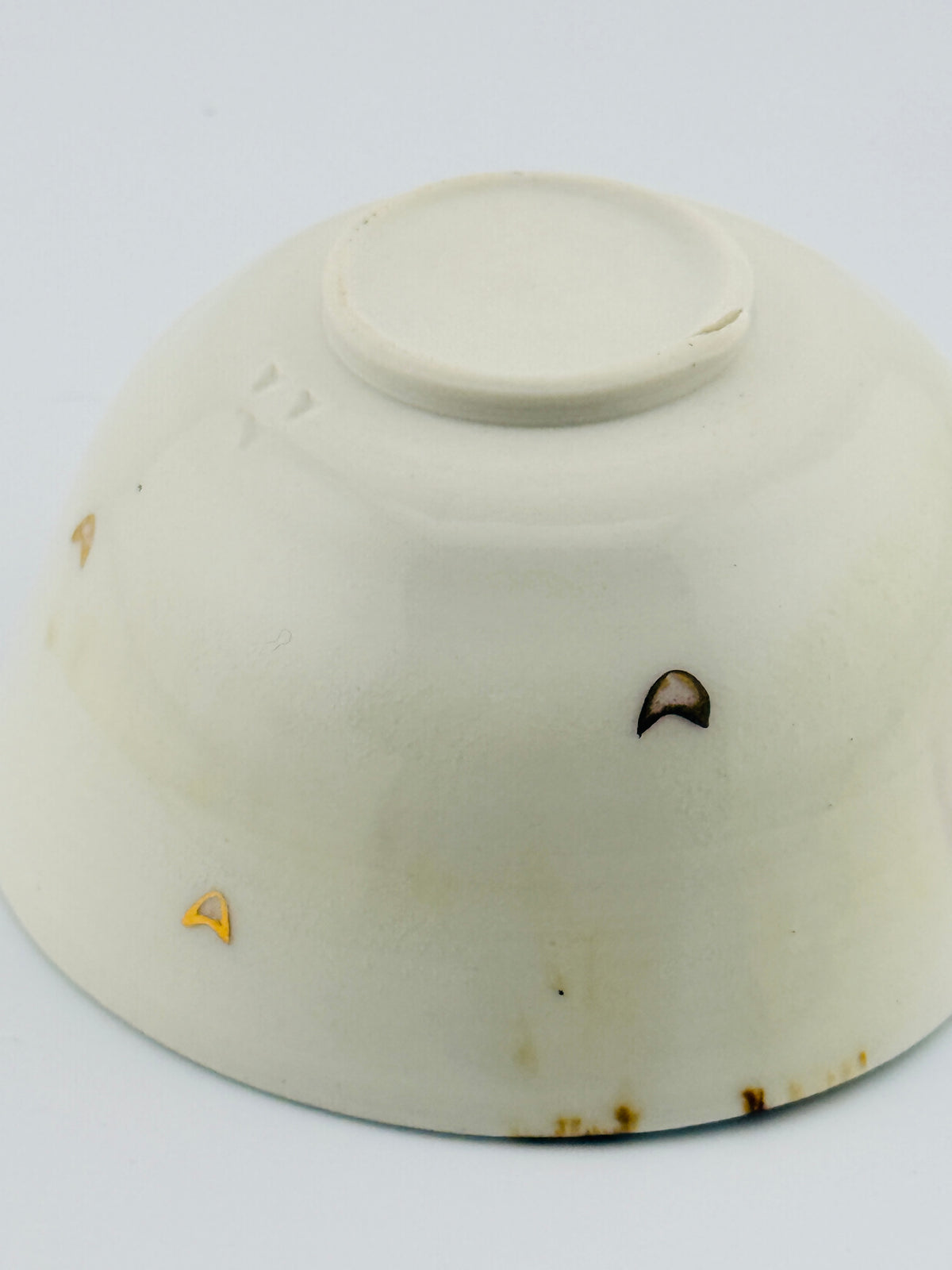 Dessous d’une tasse verseuse katakuchi blanche, avec un petit cœur à l’or