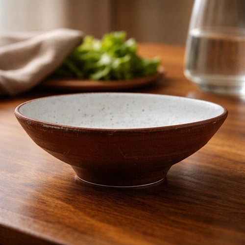 Petit saladier "Naoussa" en grès rouge de Xing avec émail blanc pyrité, mise en scène sur une table de cuisine en bois, tourné à la main par Terresme.